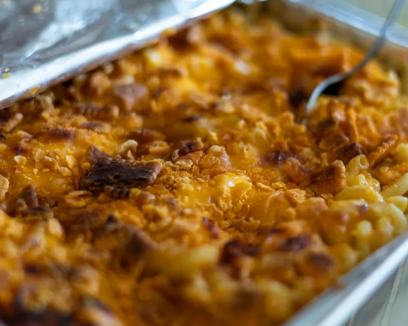 Baked mac and cheese with a browned cheese crust in a foil pan