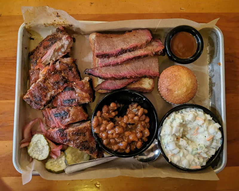 BBQ combo tray with ribs, sliced brisket, beans, coleslaw, pickles and a cornbread muffin