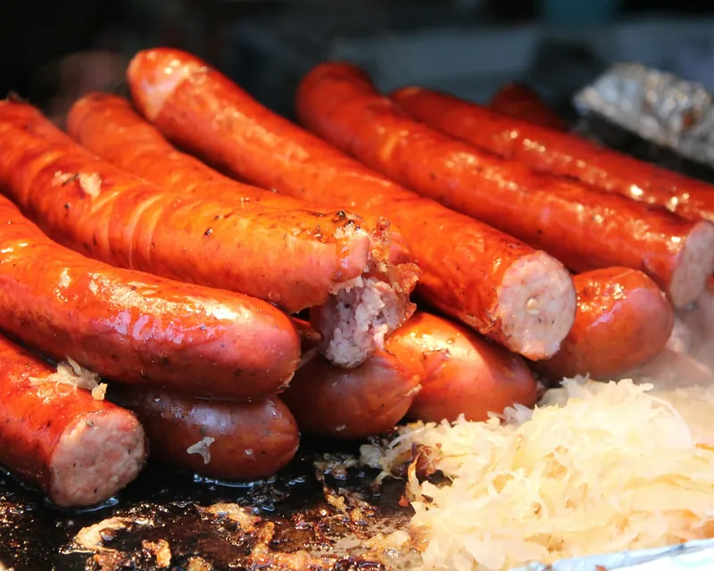 Smoked hot links piled on the grill beside sauerkraut