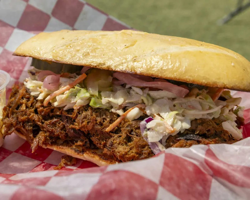 Pulled pork sandwich topped with coleslaw in a checkered paper basket