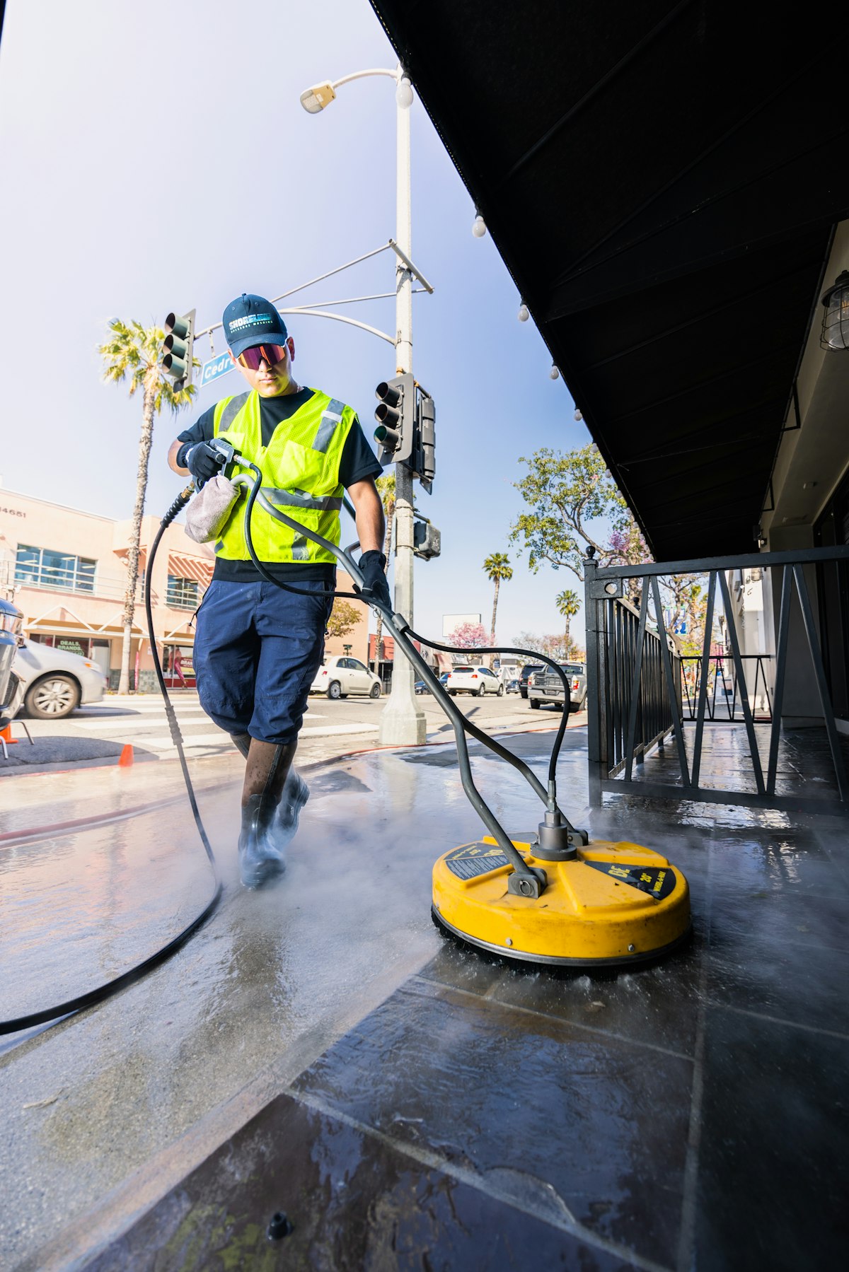 Worker cleaning a street surface with a high-pressure washer